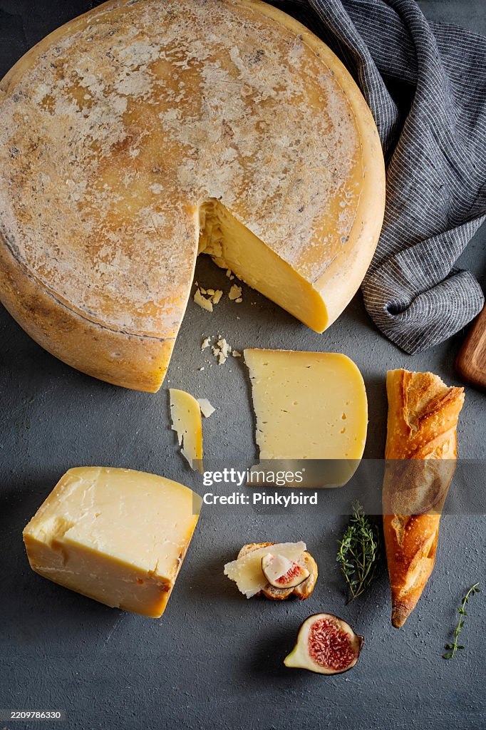 Forma di formaggio kasar stagionato. Forma di formaggio. Formaggi artigianali. Forma di formaggio con pane e fichi. Intera forma di formaggio su sfondo blu scuro. Forma intera con la fetta di spicchio rimossa.