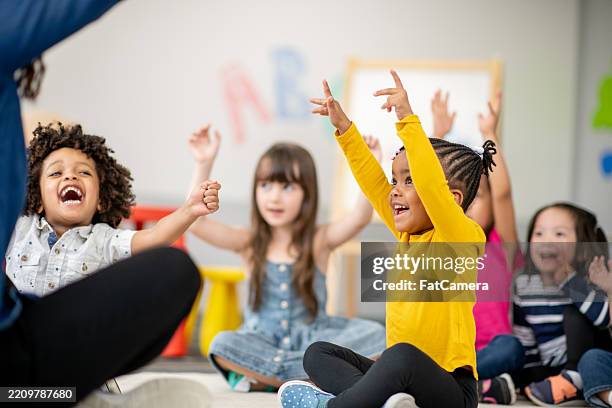children sitting on the floor participating in a fun classroom activity - preschool student stock pictures, royalty-free photos & images