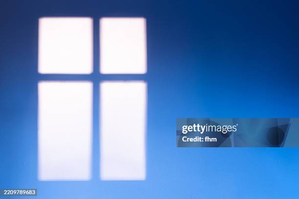 bright shade of a window on a blue wall - fensterrahmen stock-fotos und bilder
