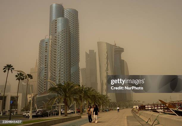 People walk amidst a heavy sandstorm at Doha Corniche in Doha, Qatar, on April 15, 2025.
