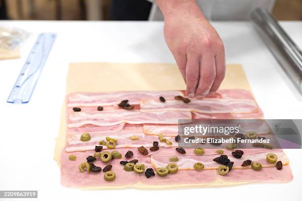 baker's hand adding raisins and olives to traditional venezuelan ham bread filling - cultura de venezuela fotografías e imágenes de stock