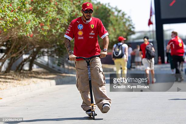 Lewis Hamilton of Great Britain and Ferrari rides a scooter in the paddock during qualifying ahead of the F1 Grand Prix of Bahrain at Bahrain...