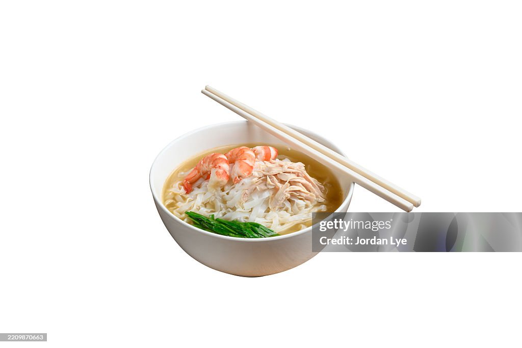 Bowl of flat rice noodle in soup with shredded chicken on white background