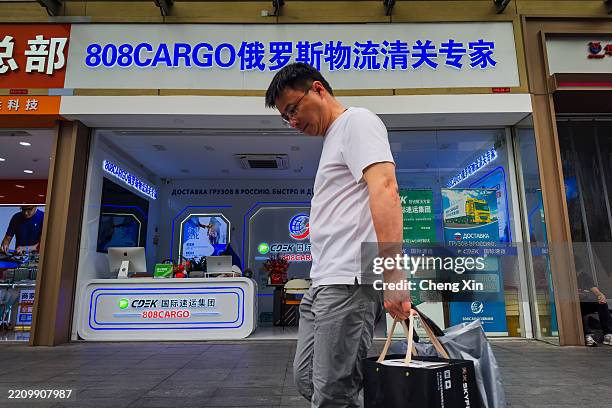 Man walks past the storefront of 808CARGO, a logistics company specializing in customs clearance and shipping services to Russia, with signage in...