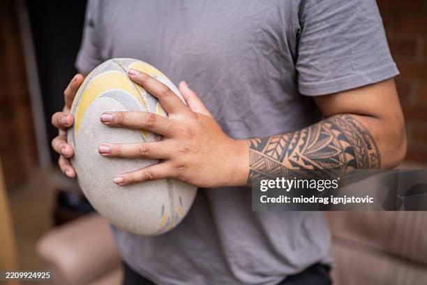 polynesian man with tribal tattoos holding rugby ball - polynesian people stock pictures, royalty-free photos & images