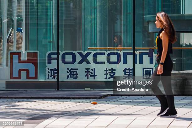 Woman walks past the logo of multinational tech company Foxconn , which is a major manufacturer for Apple products, in Taipei, Taiwan, on April 16,...