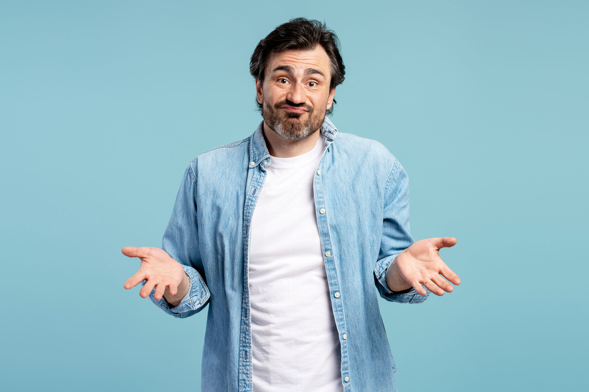 Homem confuso encolhendo os ombros gesticulando que eu não sei no fundo azul Homem confuso encolhendo os ombros gesticulando que eu não sei no fundo azul