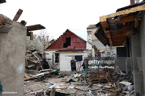 Two men stand among the rubble in the yard of a house damaged by an overnight Russian drone attack in Odesa, Ukraine, on April 16, 2025. Russian...