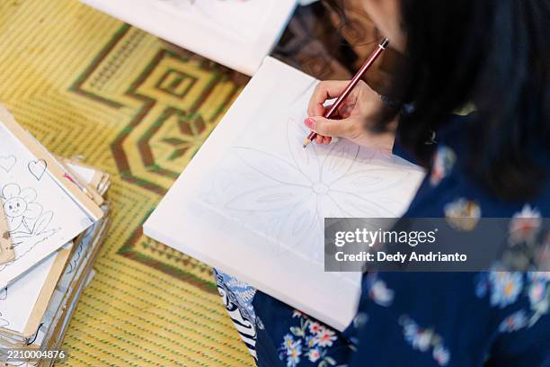 hands drawing batik pattern on fabric at traditional workshop - batik pattern stock pictures, royalty-free photos & images
