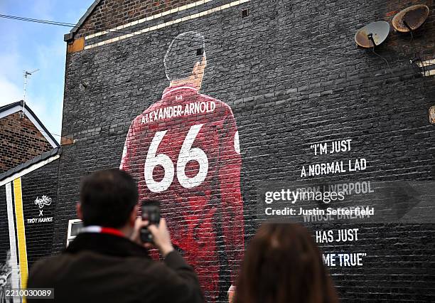 Fans of Liverpool take a picture of a mural which features Trent Alexander-Arnold of Liverpool on the side of a house prior to the Premier League...