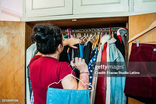 young woman choosing clothes in wardrobe at home - decluttering stock pictures, royalty-free photos & images