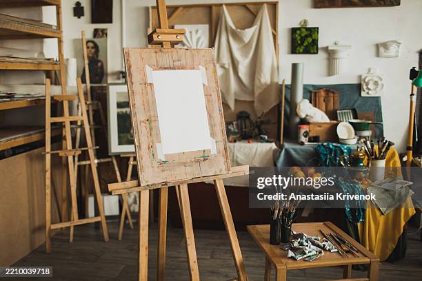 art studio workspace featuring easel, brushes, and creative supplies - kunstatelier stockfoto's en -beelden