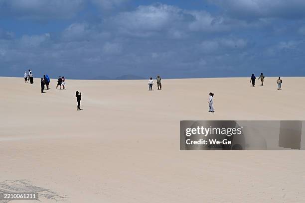 touristen und einheimische wandern durch die sanddünen entlang der küste im naturpark der dünen von corralejo auf fuerteventura. - naturpark stock-fotos und bilder