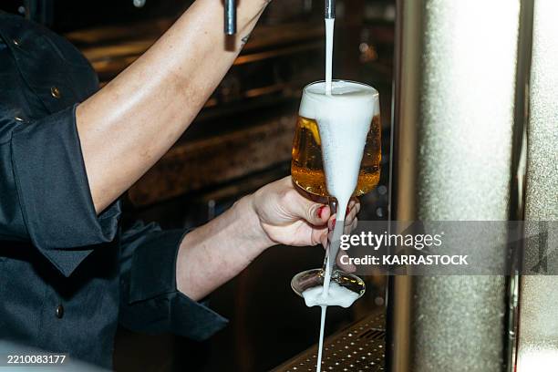 bartender pouring beer into glass - frothy drink stock pictures, royalty-free photos & images