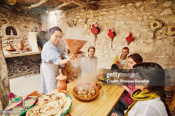 wide shot instructor lifting lid of cooked tajine in cooking class - tradition stock pictures, royalty-free photos & images