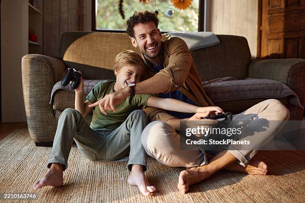 happy father and son having fun while playing video games at home. - videospel stockfoto's en -beelden
