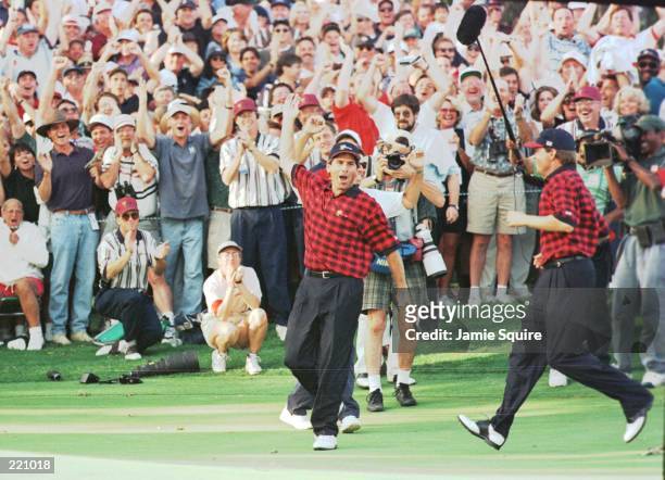 Team members Fred Couples and Davis Love III visibly react in celebration following Couples winning birdie putt on the 17th holed during the final...