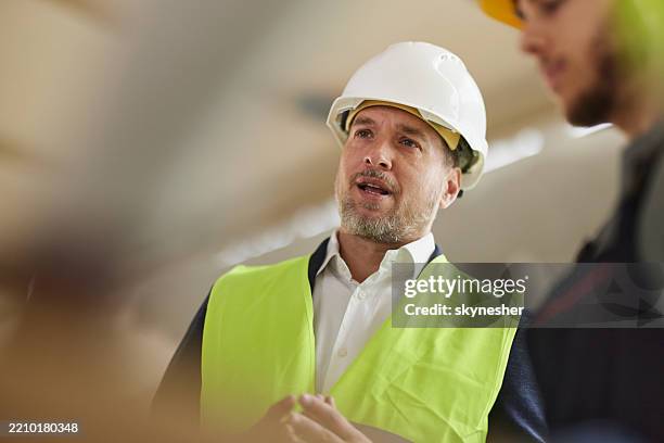 male architect talking at construction site. - hard hat stock pictures, royalty-free photos & images