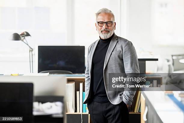 confident male architect standing in modern open-plan office space - homme 60 ans portrait photos et images de collection