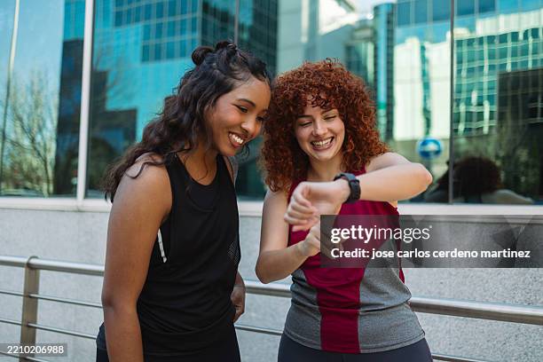 two young women runners checking smartwatch after training - fitness tracker stock pictures, royalty-free photos & images