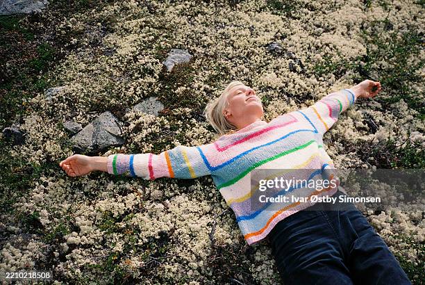 woman lying on soft ground with arms outstretched - langzaam stockfoto's en -beelden