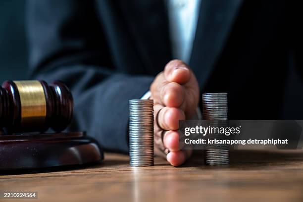 concept of saving money and investment growth. lawyer's hand holding coins on a pile of coins. division of assets.,concept of saving and investing. - dividir fotografías e imágenes de stock