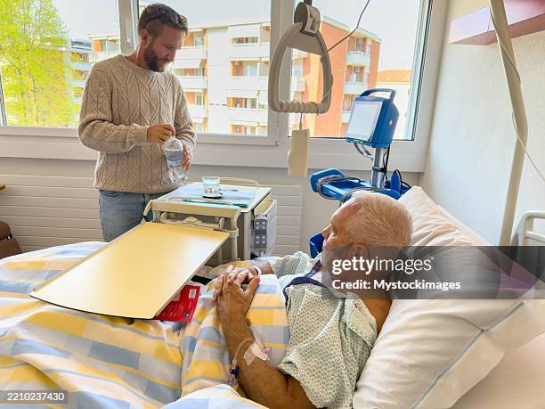 caring visitor assisting elderly patient in hospital room - health monitoring stock pictures, royalty-free photos & images