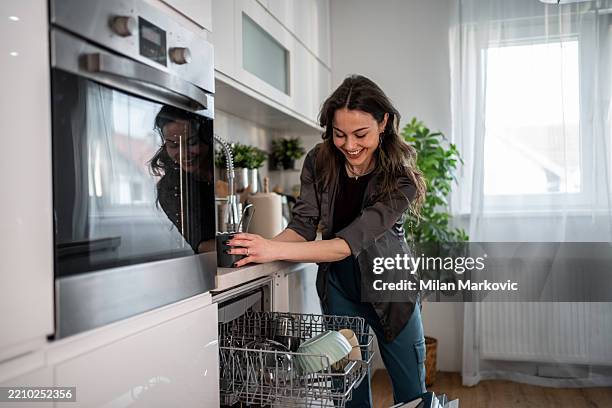 young woman emptying dishwasher in modern kitchen - home economics class stock pictures, royalty-free photos & images