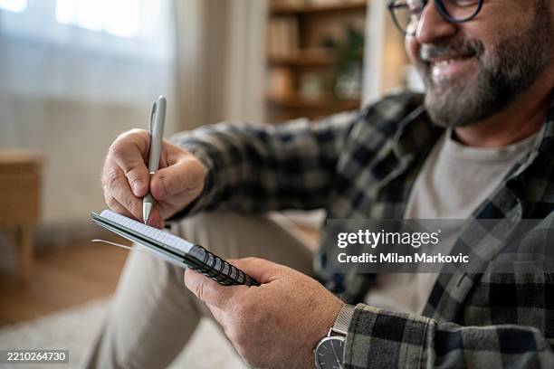 mature man taking notes in notepad at home - to do list stock pictures, royalty-free photos & images