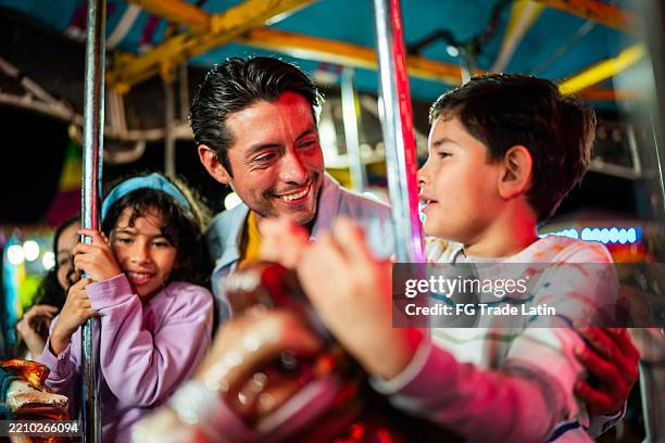 family talking on carousel at amusement park - joy ride stock pictures, royalty-free photos & images