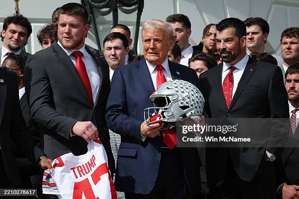 President Donald Trump reacts as U.S. Vice President JD Vance drops part of the Championship Trophy during a ceremony welcoming the 2025 College...