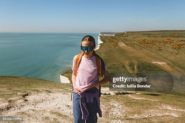 teen girl standing on coastal cliff path with scenic ocean view - seven sisters klif stockfoto's en -beelden