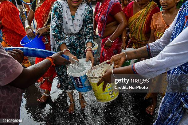 People fill containers on the streets from a municipal water tanker to escape from the summer heat during a Hindu festival in Kolkata, India, on...