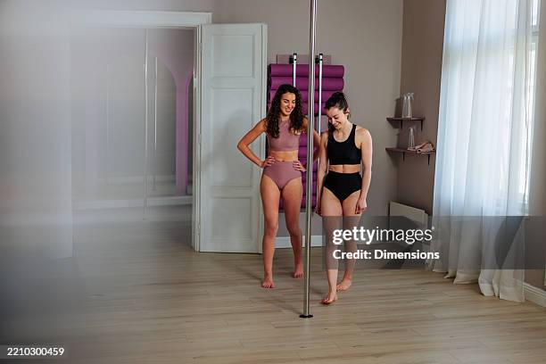 two young women practicing pole dance in a studio - pole dance stock pictures, royalty-free photos & images