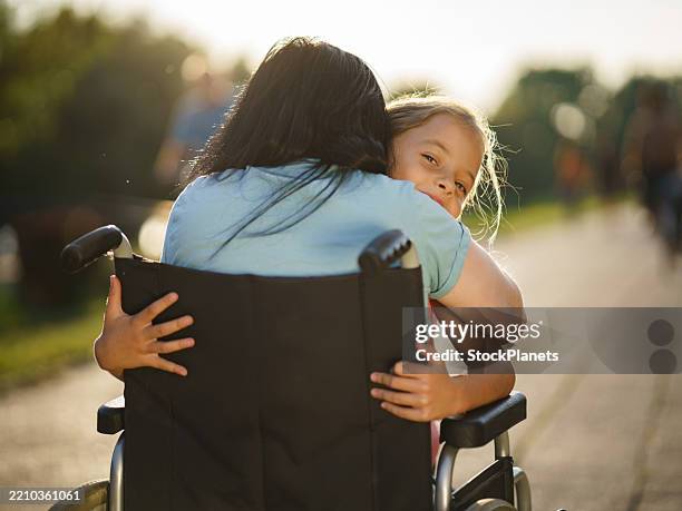 girl embracing her mother in wheelchair - paraplegic stock pictures, royalty-free photos & images