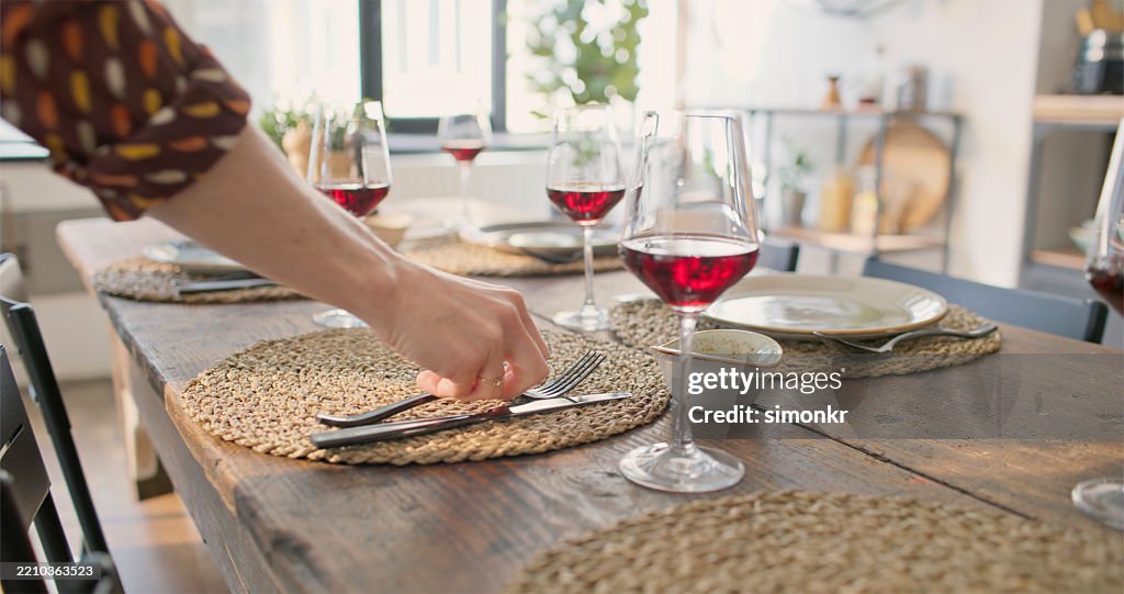 Elegante configuración de mesa de comedor con detalles de madera y vino tinto en un interior luminoso