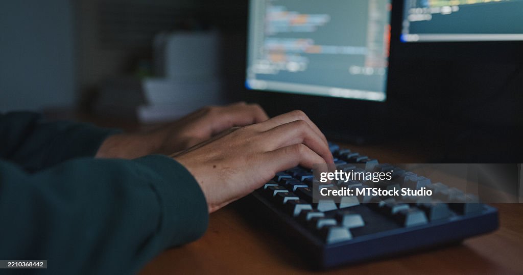 Closeup of young man software engineer working late on AI prompts and web designs coding on computer in bedroom at home night. Software developer, artificial intelligence and programmer.