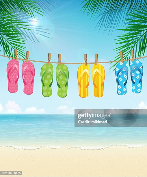 bunte flip-flops, die an einer wäscheleine an einem tropischen strand hängen - hitzefrei stock-grafiken, -clipart, -cartoons und -symbole