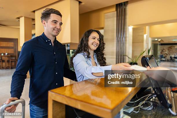 una joven pareja se registra en la recepción del hotel. - motel pareja fotografías e imágenes de stock