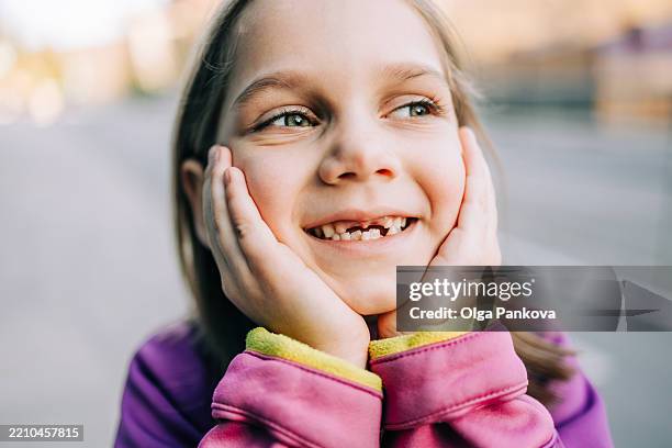 cute girl smiling without front teeth and holding face - losing teeth stock pictures, royalty-free photos & images