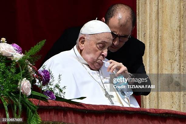 Pope Francis sips water with a straw on the main balcony of St. Peter's basilica during the Urbi et Orbi message and blessing to the city and the...
