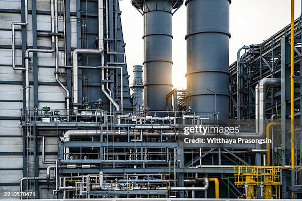 industrial facility with metal pipes and structural components at sunrise - gas refinery stock pictures, royalty-free photos & images