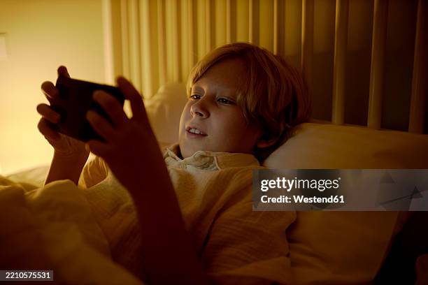 boy playing on a smartphone in bed at night - eagle ray stock pictures, royalty-free photos & images