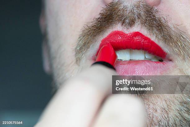 man with beard applying red lipstick as a form of self-expression - stereotype stock pictures, royalty-free photos & images