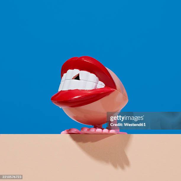 red mouth with a chipped tooth on a wall against a blue background representing dental care - offbeat stock pictures, royalty-free photos & images