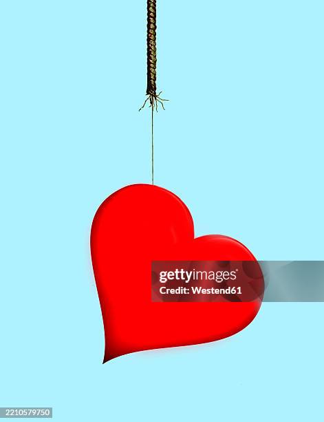 red heart hanging on a rope against a blue background symbolizing love and relationships - falling in love stock illustrations