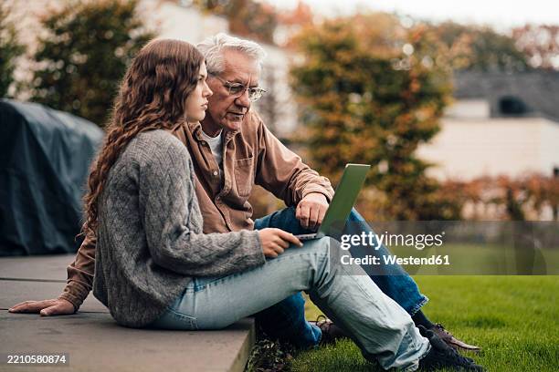 grandfather and granddaughter planning sustainable energy projects in the garden - granddaughter stock pictures, royalty-free photos & images