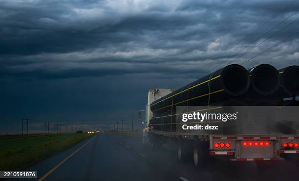 flatbed tractor trailer semi-truck driving on a stormy and rainy evening - moody sky stock pictures, royalty-free photos & images