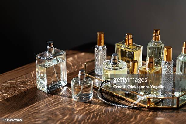 elegant display of various perfume bottles arranged on a wooden surface with soft lighting - perfume stock pictures, royalty-free photos & images