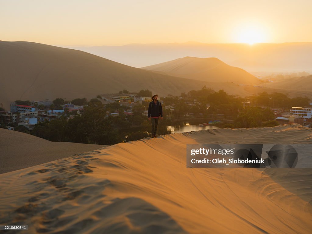 Man walking in the desert during experiential trip in Huacachina, Peru